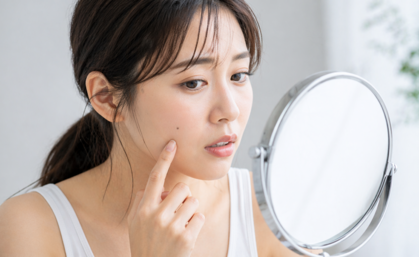 顔のほくろを鏡で確認する女性