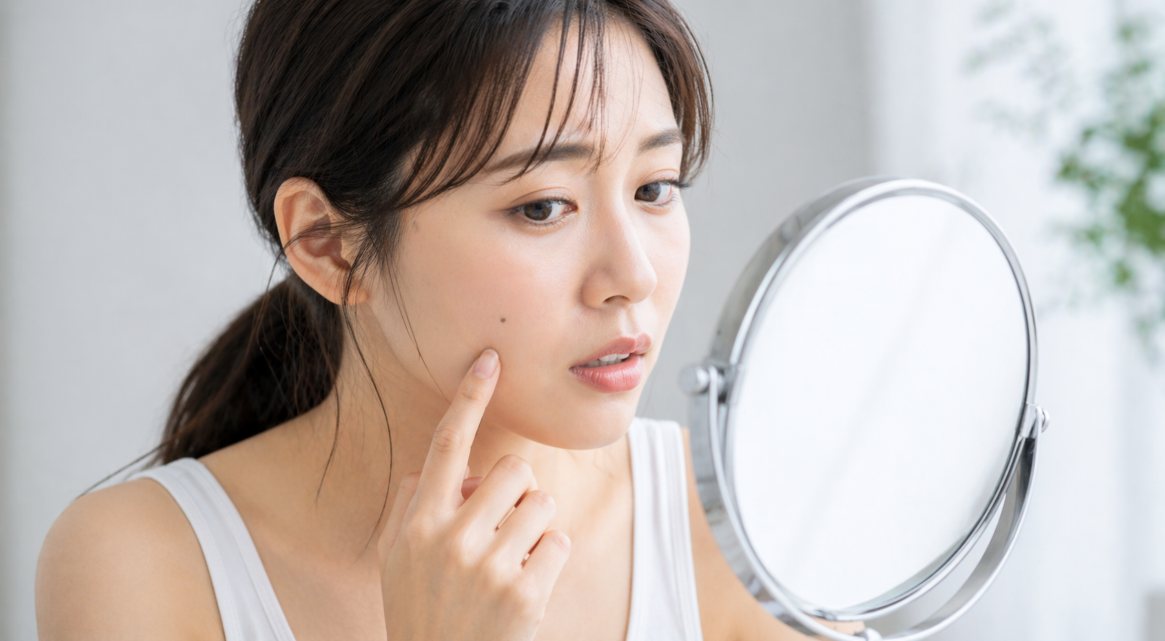 顔のほくろを鏡で確認する女性