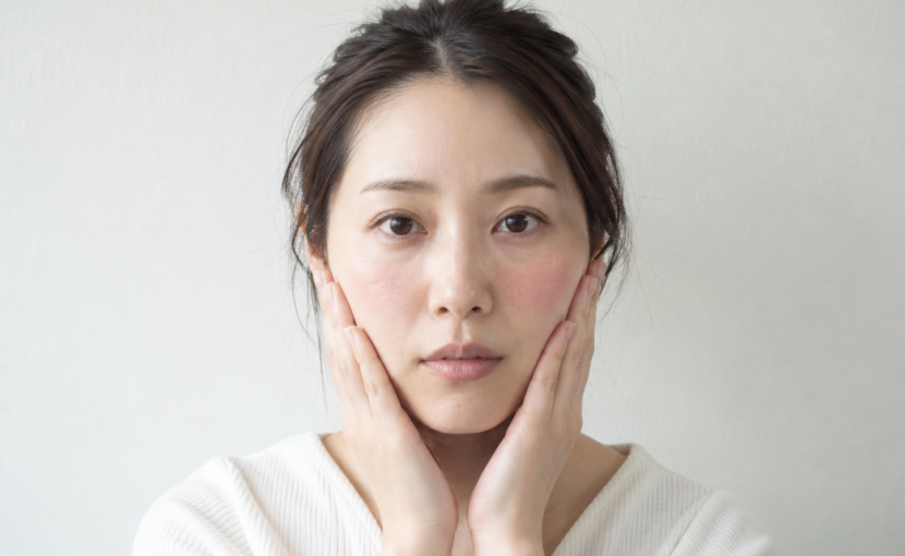 赤みのある頬に両手を添えている女性