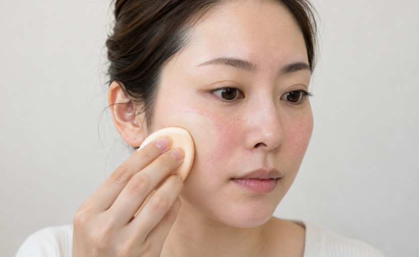 頬の赤みをファンデーションで隠している女性