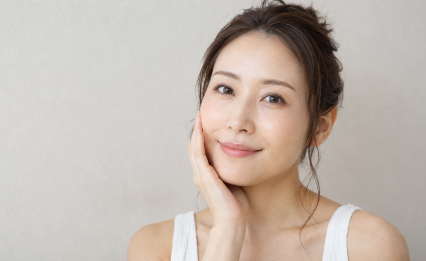 自分の頬を触って微笑む女性